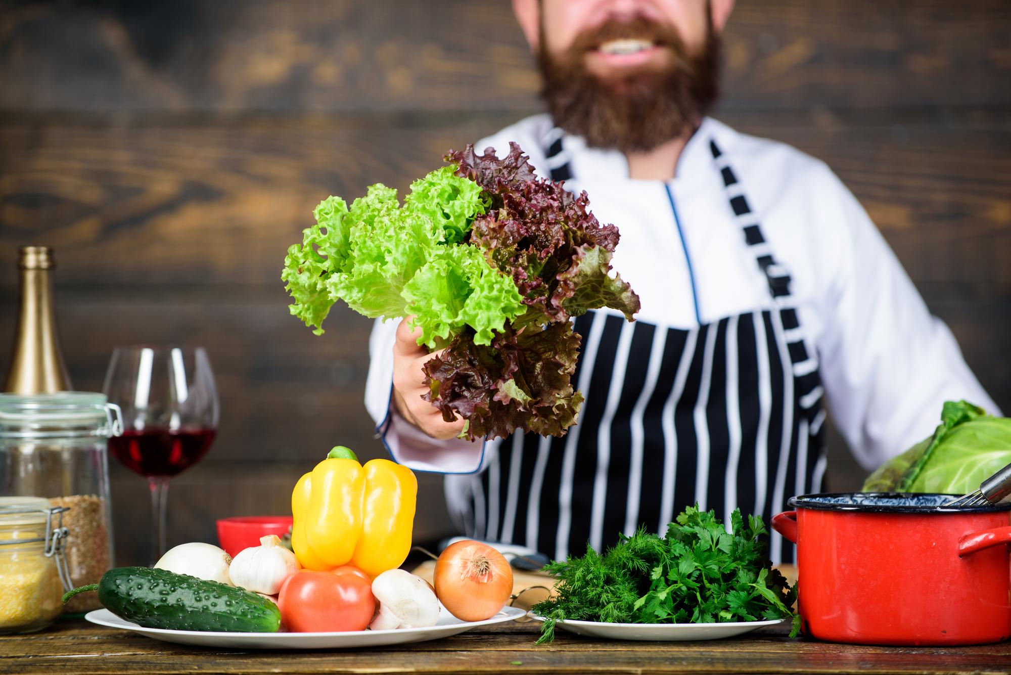 Chef arranging colorful local produce on wooden table